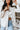 Front view of model wearing the Tell Me Everything Suede Shacket, which features a cream suede material, a collar neck, a button-up front, long cuffed sleeves, two front pockets, and a curved bottom hem. Shacket is unbuttoned over white brami