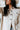 Close-up front view of model wearing the Tell Me Everything Suede Shacket, which features a cream suede material, a collar neck, a button-up front, long cuffed sleeves, two front pockets, and a curved bottom hem. Shacket is half buttoned