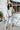 Full body front view of model wearing the Tell Me Everything Suede Shacket, which features a cream suede material, a collar neck, a button-up front, long cuffed sleeves, two front pockets, and a curved bottom hem