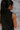 Back detail view of model wearing The Midnight Magic Feather Dress features black fabric, a mock neckline, a sleeveless a-line silhouette, and a feather-trimmed hemline.
