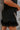 Bottom feather detail view of model wearing The Midnight Magic Feather Dress features black fabric, a mock neckline, a sleeveless a-line silhouette, and a feather-trimmed hemline.