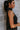 Side view of model wearing The Midnight Magic Feather Dress features black fabric, a mock neckline, a sleeveless a-line silhouette, and a feather-trimmed hemline.