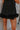 Bottom feather detail view of model wearing The Midnight Magic Feather Dress features black fabric, a mock neckline, a sleeveless a-line silhouette, and a feather-trimmed hemline.