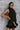 Front view of model wearing The Midnight Magic Feather Dress features black fabric, a mock neckline, a sleeveless a-line silhouette, and a feather-trimmed hemline.