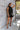 Front view of model wearing The Midnight Magic Feather Dress features black fabric, a mock neckline, a sleeveless a-line silhouette, and a feather-trimmed hemline.