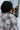 Close-up back view of model wearing the Coffee Date Plaid Shacket, that has a white, taupe, rust, and blue plaid print, a button front with a collar, tortoise buttons, 2 front chest pockets, and long sleeves. Worn over a white brami.