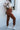 Full body side view of model wearing Running Up That Hill Joggers features a brown colored nylon material, a high-rise fit, a thick elastic waist with an adjustable tie, side pockets, and a jogger fit.
