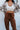 Close-up front view of model wearing Running Up That Hill Joggers features a brown colored nylon material, a high-rise fit, a thick elastic waist with an adjustable tie, side pockets, and a jogger fit.