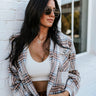 Front view of model wearing the Coffee Date Plaid Shacket, that has a white, taupe, rust, and blue plaid print, a button front with a collar, tortoise buttons, 2 front chest pockets, and long sleeves. Worn over a white brami.