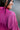 Close-up back/top view of model wearing the Dancing Queen Dress, that has a fuchsia textured material, a satin collar neck, a button-up front, long cuffed sleeves, an adjustable tie belt, and lettuce edge bottom hem.