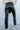 Back view of 5'8 model wearing the Next Level Straight Leg Pants features a black faux-leather material, a high-rise fit, a clasp and zipper front closure, belt loops, two front pockets, a middle seam down the legs, and a straight leg fit