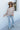 Full body view of model wearing the Ever After Floral Top, which features mocha-colored fabric with white, blue, and rust floral print, a notched v-neckline, long sleeves with elastic wrists, and a flowy fit.