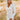front view of model wearing the Daydreamer Faux Leather Dress, that has an ivory PU material, a surplice neckline, shoulder pads, long sleeves, a draped front, a back zipper closure, and a mini length