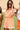 Full body view of model wearing the Tatum Orange and Cream Checkered Romper. This is an orange and cream checkered romper, with short sleeves, button up front, and a collared neckline.