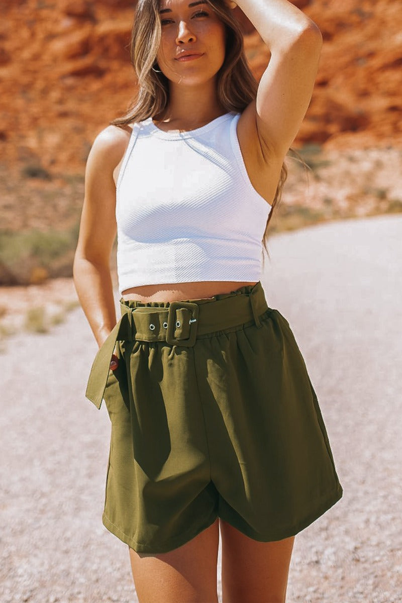 Frontal view of the Livin' The Dream Shorts that features an olive green colored material, a high-rise fit, an elastic waist, a belt detail, side pockets, and a flowy fit.