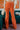Frontal view of the Missed Decade Flare Pants that features an orange colored corduroy material, a high-rise waist, a button and zipper front closure, faux front pockets, two back pockets, and a flare fit.