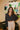 Frontal view of the Nothing On You Top that features a black material, a white plaid pattern, a collar neck, a button-up front, long sleeves, two front pockets, a front knot detail at the hemline, and an elastic hemline in the back.