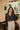 Frontal view of the Nothing On You Top that features a black material, a white plaid pattern, a collar neck, a button-up front, long sleeves, two front pockets, a front knot detail at the hemline, and an elastic hemline in the back.