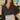 Frontal view of the Nothing On You Top that features a black material, a white plaid pattern, a collar neck, a button-up front, long sleeves, two front pockets, a front knot detail at the hemline, and an elastic hemline in the back.