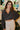 Frontal view of the Nothing On You Top that features a black material, a white plaid pattern, a collar neck, a button-up front, long sleeves, two front pockets, a front knot detail at the hemline, and an elastic hemline in the back.