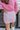 Close back view of model wearing the Shine On Sequin Skirt in Pink, which features light pink fabric with a sequined overlay, ruching on the front, and an elastic waist.