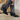 Close up right side view of a model wearing the Emersyn Western Boots, that feature black faux-leather with white western stitching, slip on entry, and 3.5" heels