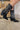 Close up right side view of a model wearing the Emersyn Western Boots, that feature black faux-leather with white western stitching, slip on entry, and 3.5" heels