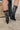 Close up back view of a model wearing the Emersyn Western Boots, that feature black faux-leather with white western stitching, slip on entry, and 3.5" heels