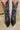 Close up front view of a model wearing the Emersyn Western Boots, that feature black faux-leather with white western stitching, slip on entry, and 3.5" heels