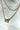 Close-up view of the Stay Golden Necklace, that features double gold chains with a clear rectangular stone.