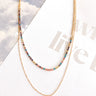 Aerial image of the Bright Idea Necklace, that features two varied gold chains and multi-colored rhinestones.