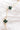 Close up image of the Emerald Dreams Necklace, that features a gold chain with emerald green rhinestone flowers.