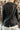 Back view of model wearing the Back To Business Blazer in Black that has  black faux-leather, a collar and lapel, and long sleeves. Worn over white blouse.