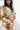 Close side view of model wearing the Warm Wishes Plaid Shacket that has brown, black and cream plaid with a cream faux-fur lining, a button-up front, a collar, two front pocket, and long sleeves. Worn unbuttoned over white top.