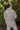 Back view of model wearing the On The Road Plaid Shacket that has taupe, cream and black plaid, a button-up front, a collar, two front chest pockets, and long sleeves. Worn unbuttoned over black top.