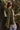 Side view of the  Destination Trip Teddy Shacket features olive lightweight teddy fabric, a snap-up front with gold buttons and a collar, chest pockets, and long sleeves with snap-closure cuffs.