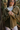 Close up view of the  Destination Trip Teddy Shacket features olive lightweight teddy fabric, a snap-up front with gold buttons and a collar, chest pockets, and long sleeves with snap-closure cuffs.