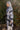 Side view of model wearing the Heading North Longline Plaid Shacket that has a black, white and grey plaid pattern, front chest pockets, a button-up front, a collar, and long sleeves. Worn over white top.