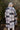 Back view of model wearing the Heading North Longline Plaid Shacket that has a black, white and grey plaid pattern, front chest pockets, a button-up front, a collar, and long sleeves. Worn over white top.