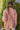 Back view of model wearing the Destination Trip Teddy Shacket in Pink that has dusty pink teddy fabric, a snap-up front, a collar, chest pockets, and long sleeves. Worn unbuttoned over white top.