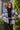 Front view of model wearing the Home For The Holidays Plaid Shacket that has black, white and grey plaid, front chest pockets, a button-up front, a collar, and long sleeves. Worn unbuttoned over black top.