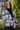 Front view of model wearing the Home For The Holidays Plaid Shacket that has black, white and grey plaid, front chest pockets, a button-up front, a collar, and long sleeves. Worn unbuttoned over black top.