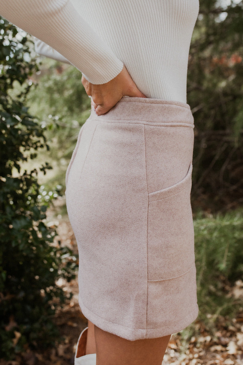 Side view of The All American Skirt In Oatmeal features oatmeal knit fabric, two front pockets, mini length, and back zipper closure.