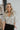 Front view of model wearing the All That Shines Top that has nude mesh fabric with silver sequin details, a cropped waist, a side zipper closure, a surplice neckline, and short sleeves