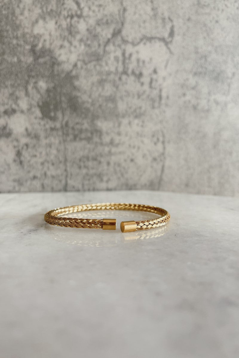 Front view of the Peyton Gold Braided Bracelet that has an open gold braided band, pictured against a marble background.