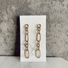 Image of the Juliette Gold Chain Link Earrings that have gold dangle hammered chains linked together, shown against a white earring card.