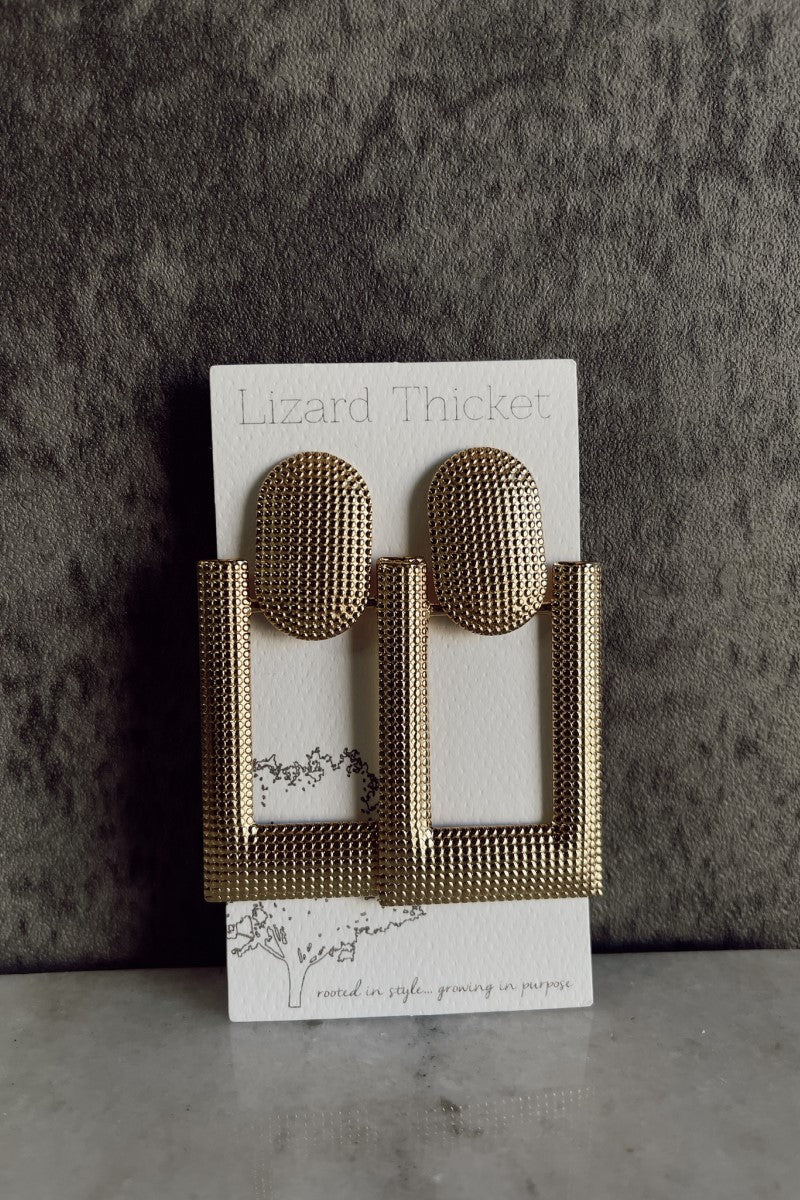 Front view of the Freya Gold Hobnail Geometric Earrings that have gold hobnail oval studs attached to open rectangle attachments, pcitures on white earring card.