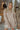 Front view of model wearing the On The Go Sweater Dress In Tan that has tan, white and grey knit fabric, a round neckline,  long sleeves, ribbed trim, and a mini-length hem