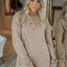 Front view of model wearing the On The Go Sweater Dress In Tan that has tan, white and grey knit fabric, a round neckline,  long sleeves, ribbed trim, and a mini-length hem