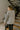 Back view of model wearing the This Is Easy Top In Grey which features grey fabric, hem detailing, high- low hem with slits, round neckline, dropped shoulders and balloon long sleeves.